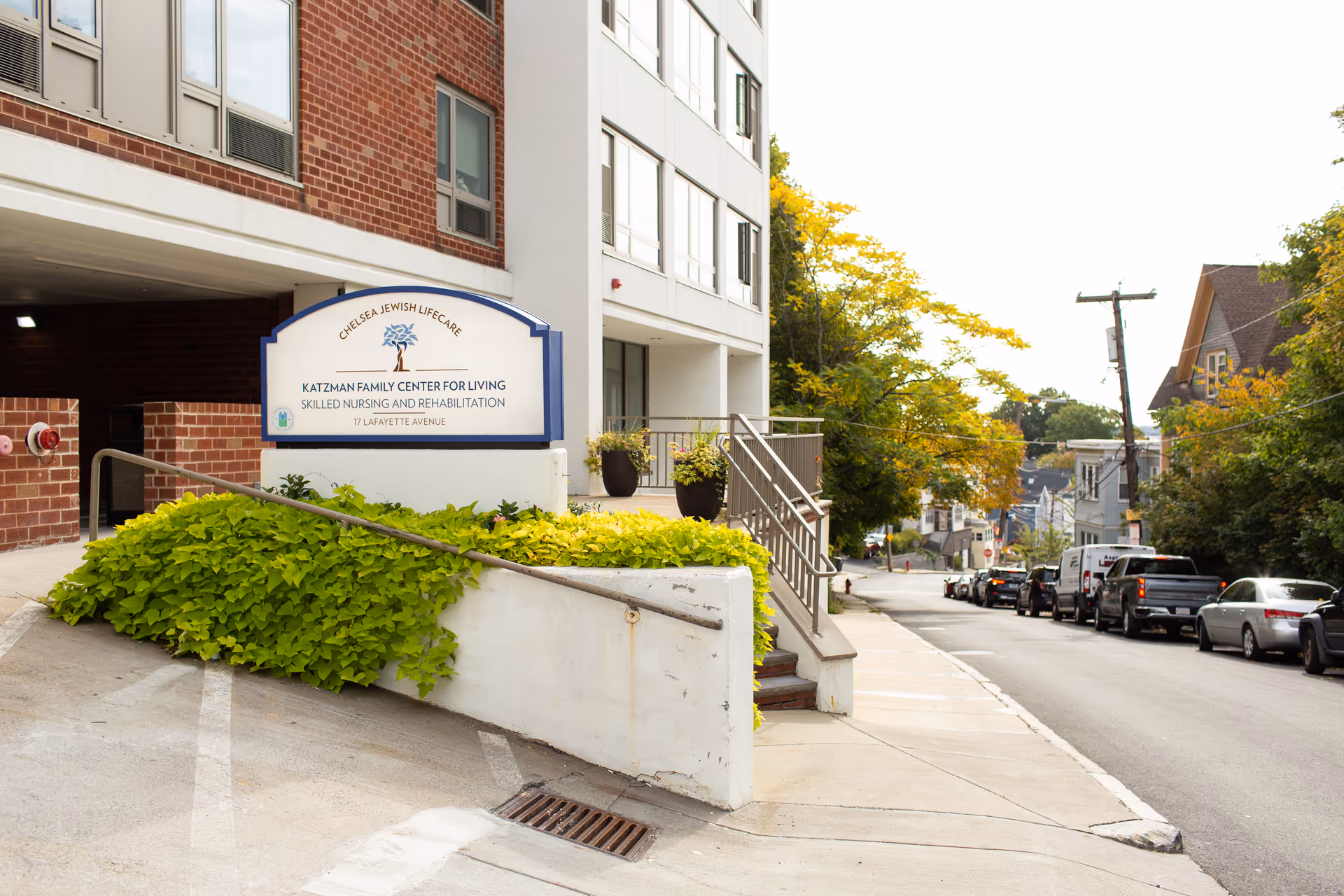 Exterior view of Katzman Family Center for Living with sign, ramp, and street.