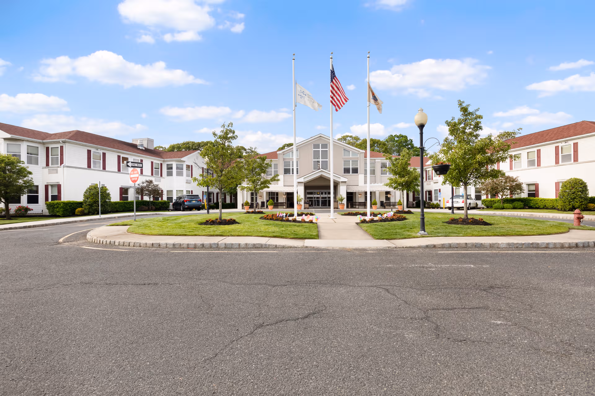 Exterior view of Complete Care at Wall facility with a circular driveway and flagpoles at entrance.