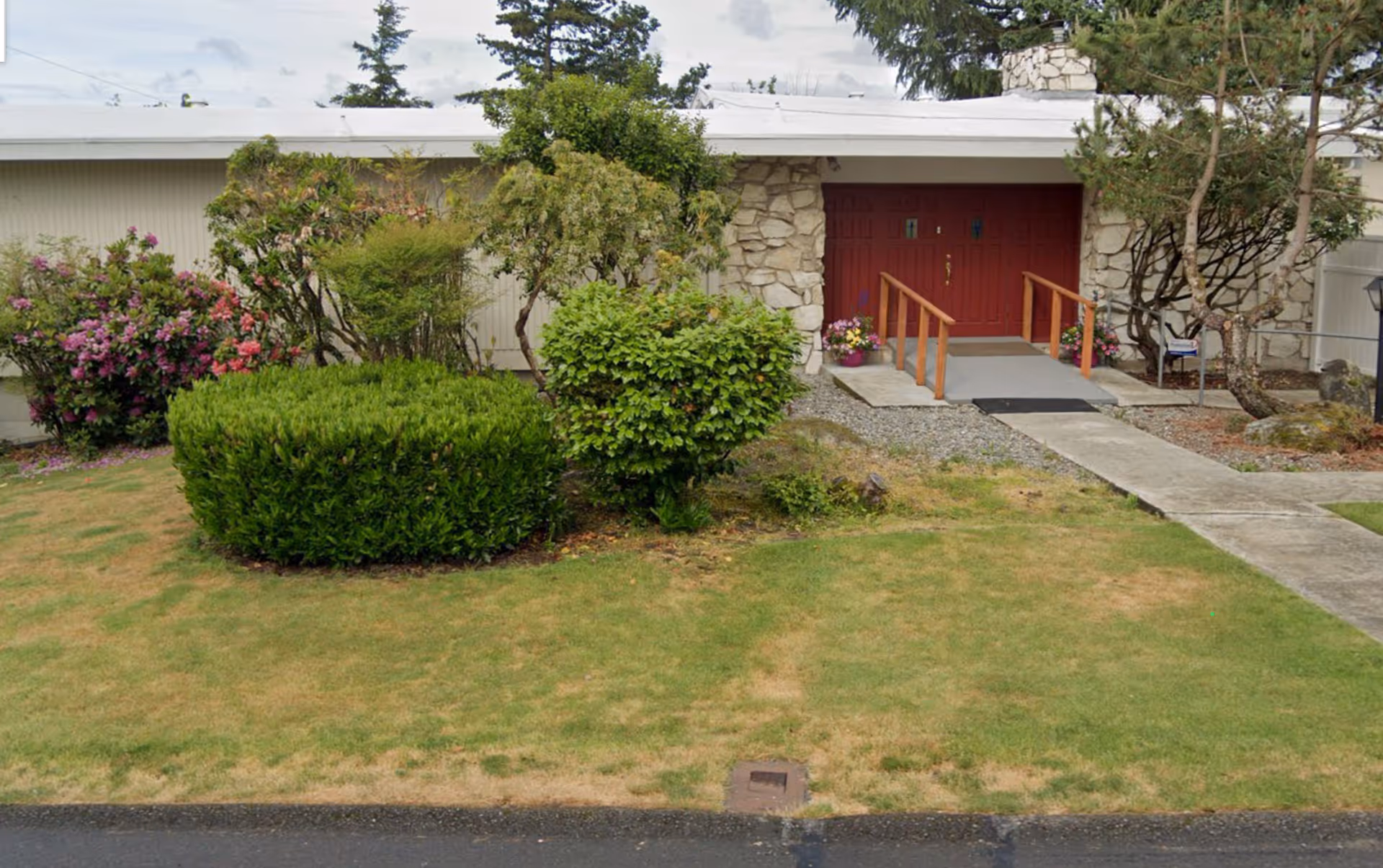 Front exterior view of Island Crest Adult Family Home with landscaped yard and red double doors