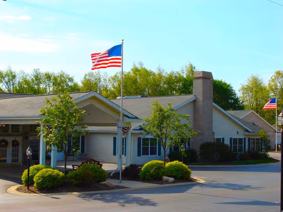 Exterior view of The Heritage Assisted Living Community with flagpoles and manicured landscaping.