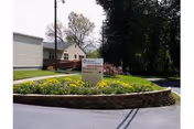 Exterior view of Mosser Nursing Home with a curved stone planter and sign.