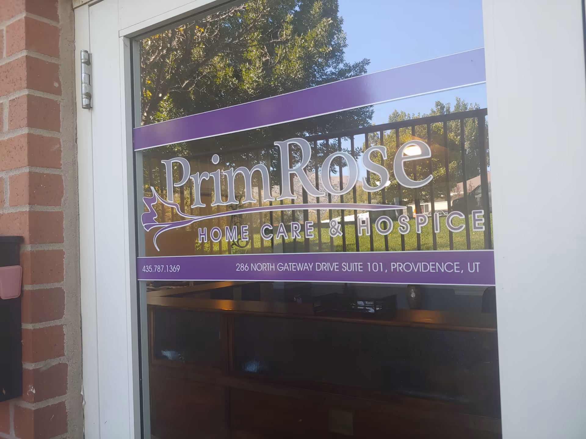 Exterior window sign for PrimRose Home Care & Hospice on brick building.