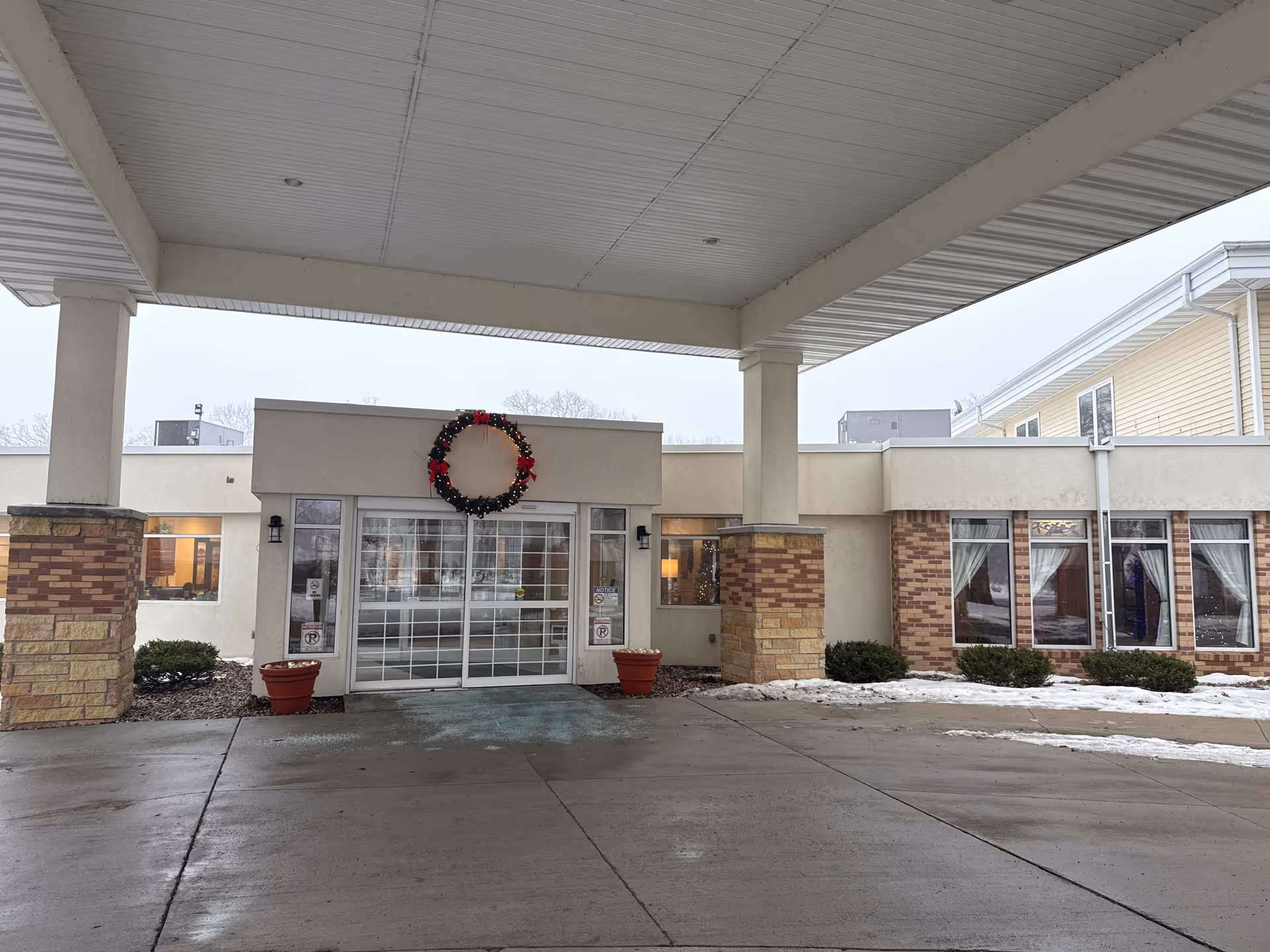 Exterior entrance of Bayside Manor senior living facility under a covered drop-off with wreath.