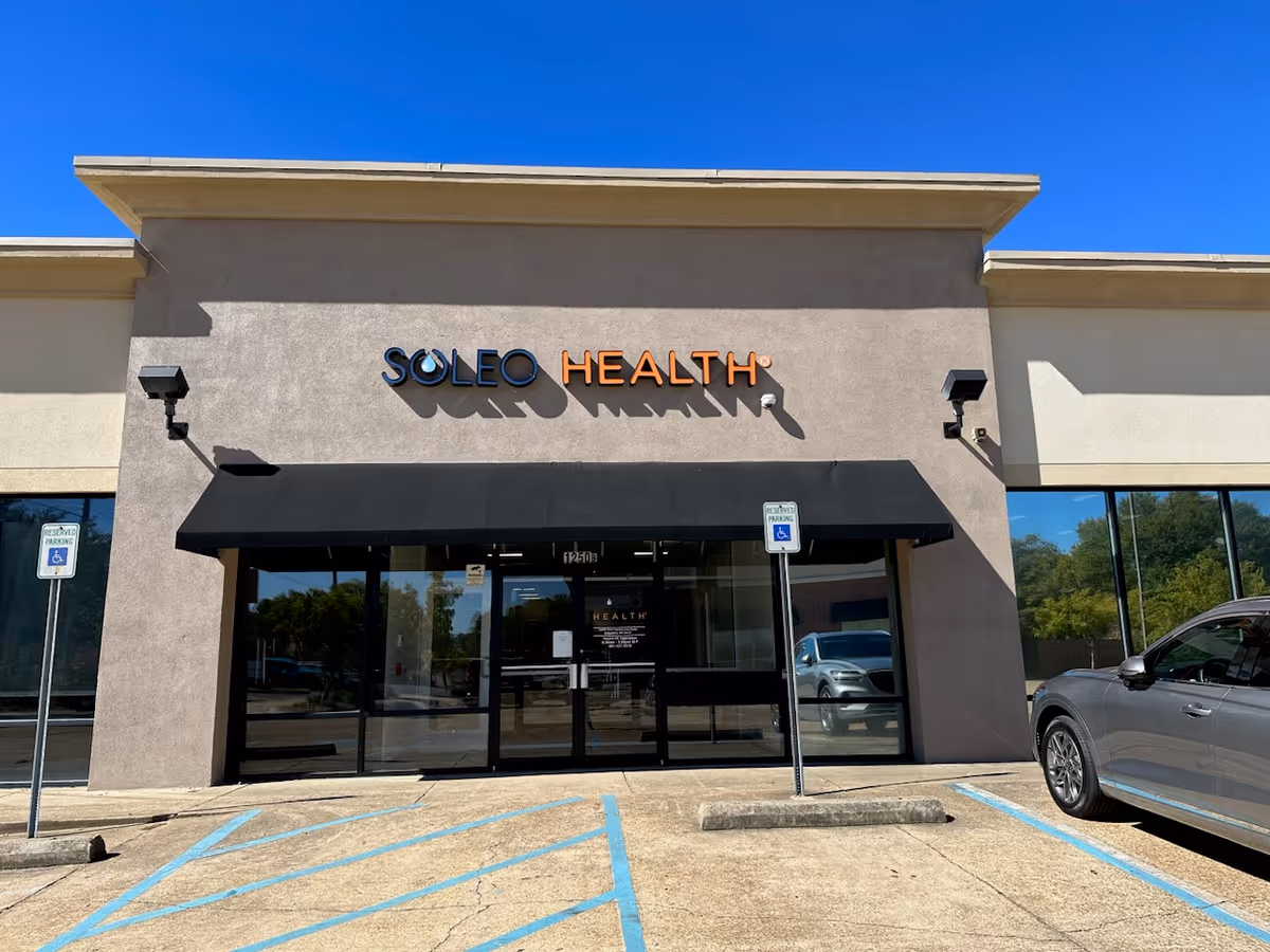 Soleo Health storefront with glass doors, black awning, and a parking lot.