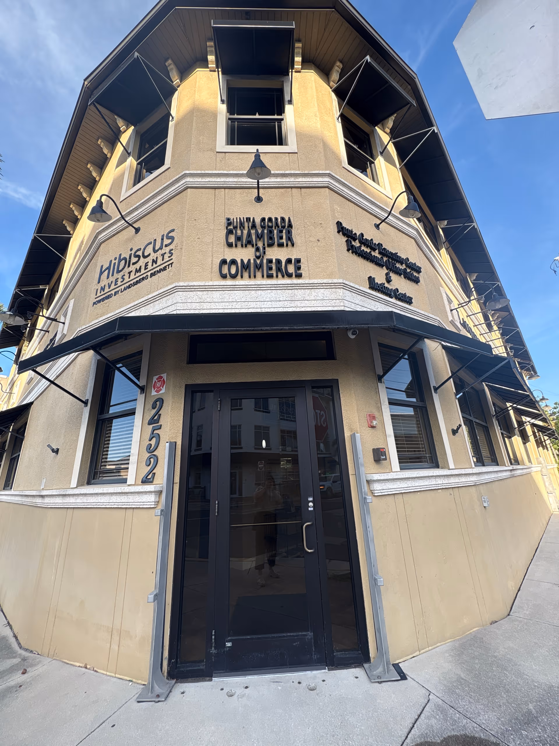 Corner view of a beige commercial building with Chamber of Commerce signage and glass door.
