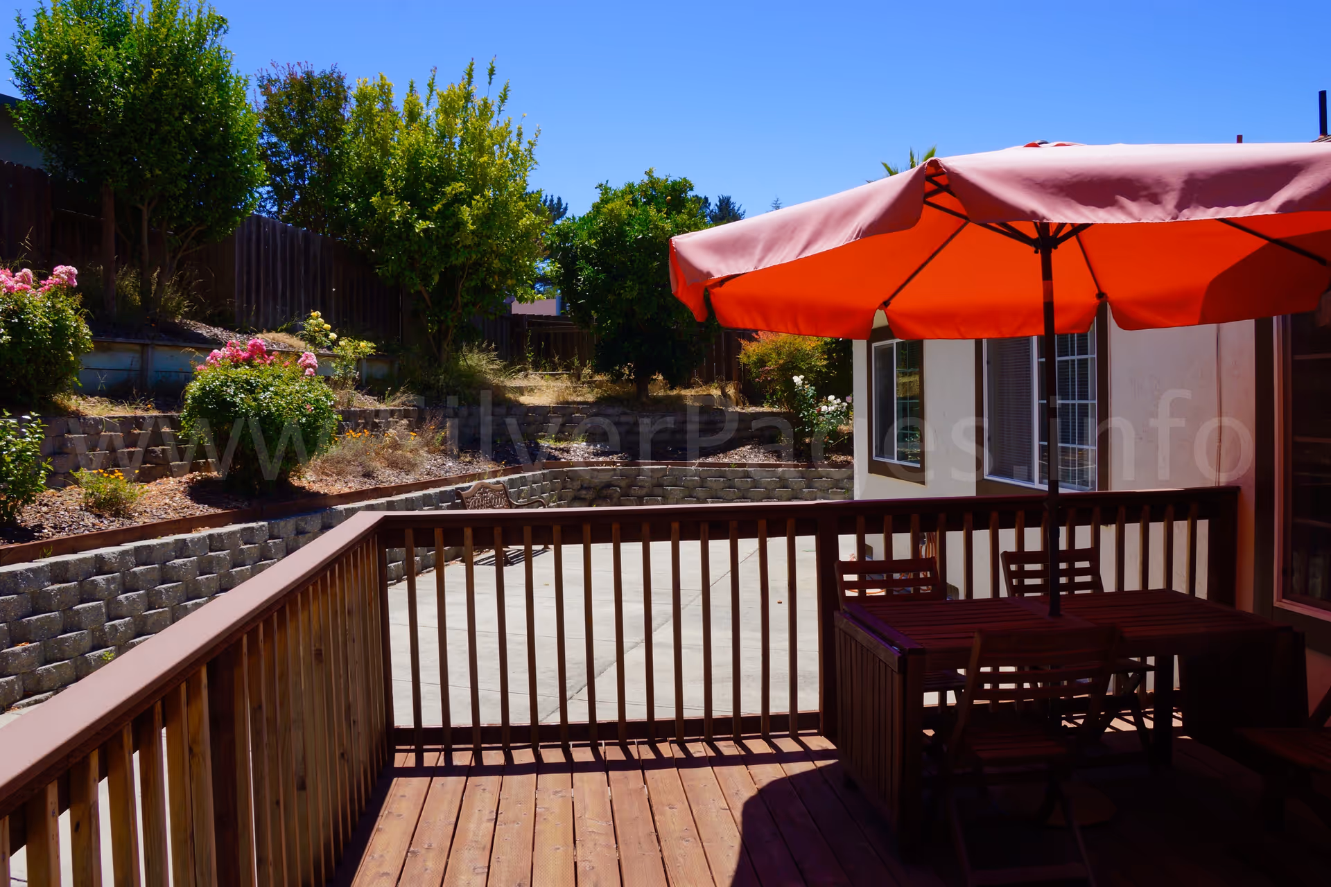 Outdoor patio on a residential deck with red umbrella and seating.