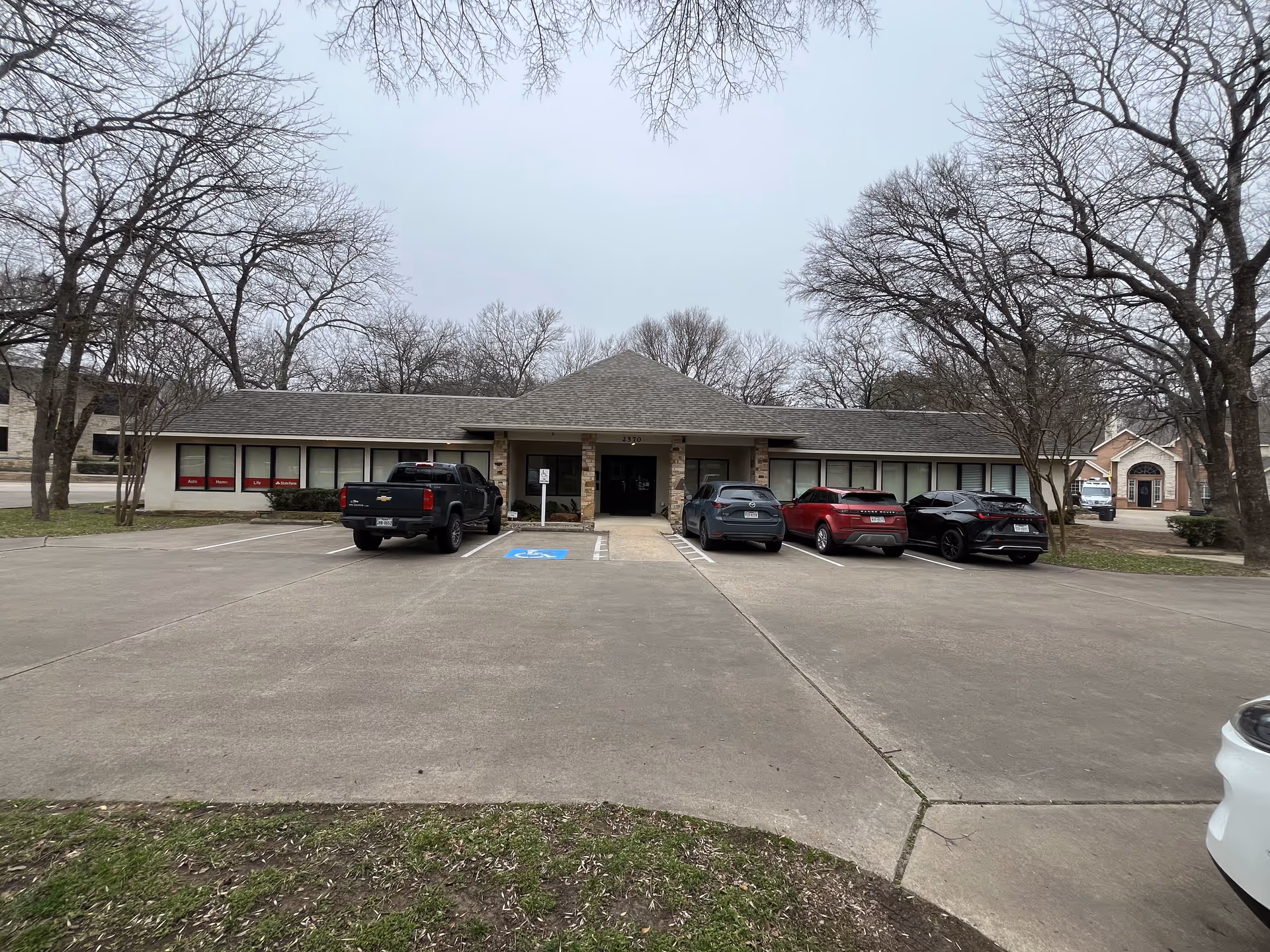 Single-story facility with a stone-entry front and several parked cars outside.