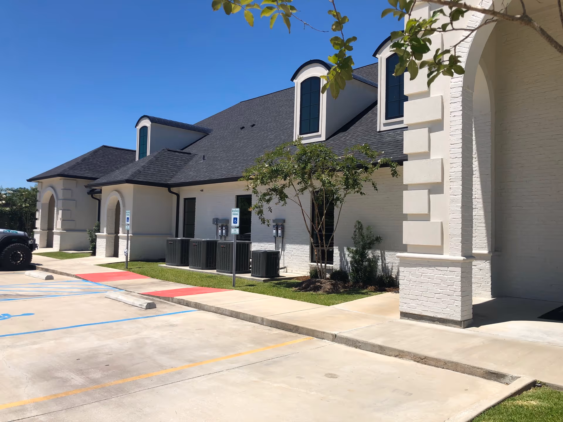 Exterior view of a modern senior living facility with parking lot and landscaping.