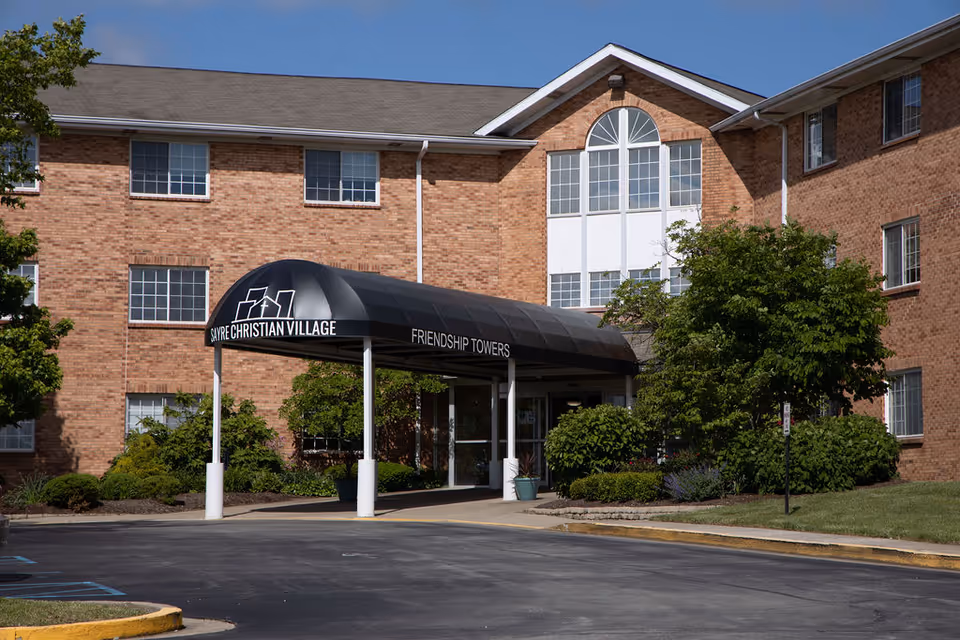 Brick senior living building with curved black entrance canopy at Sayre Christian Village