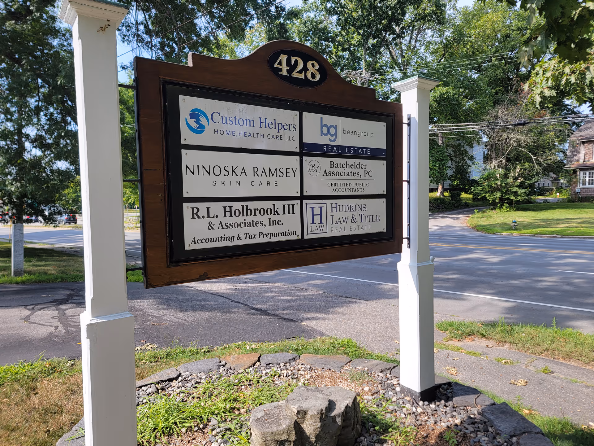 Exterior signboard displaying Custom Helpers Home Health Care among other business logos.