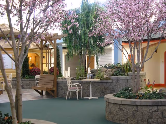 Outdoor courtyard with pink blossoms, stone planters, benches, and seating at Renvilla Health Center.