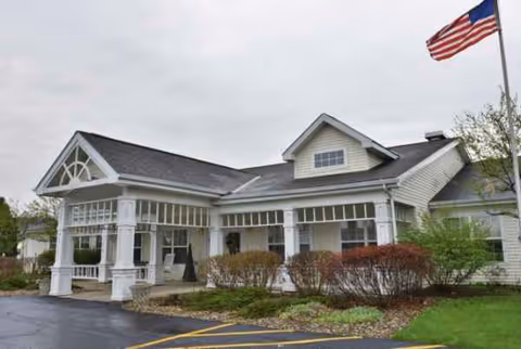 Exterior view of Trustwell Living at Carlisle Place, showing a porch and American flag.