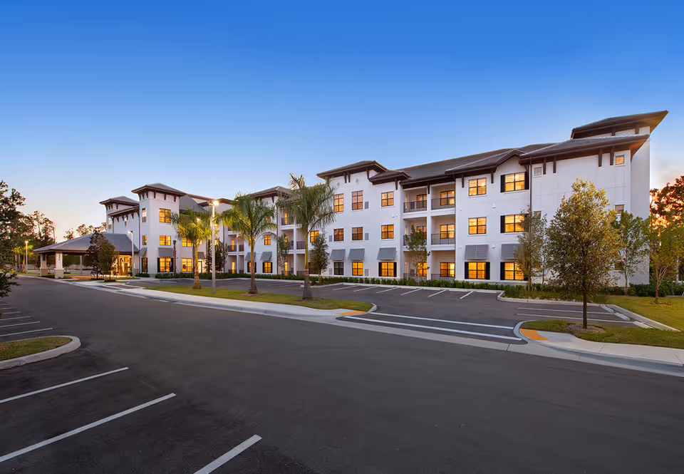 Exterior view of Seascape at Naples senior living building with parking and palm trees.