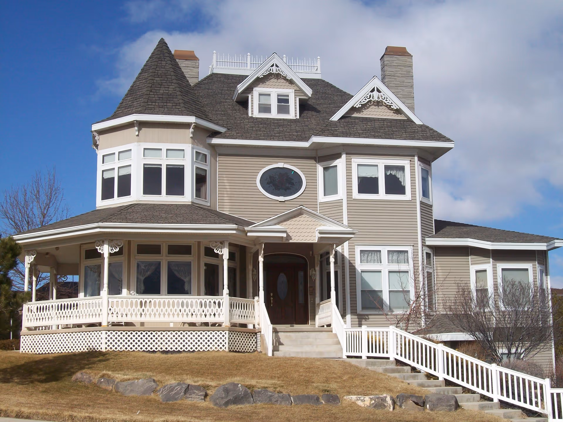 A large Victorian-style senior living building with wraparound porch and stairs.