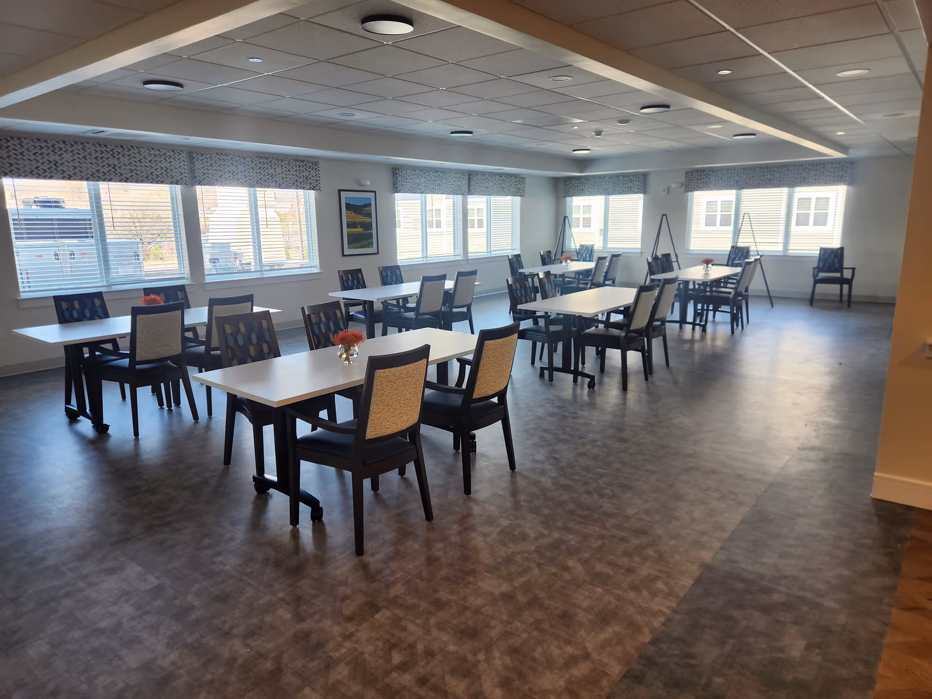 Spacious dining room with multiple tables and chairs near bright windows.