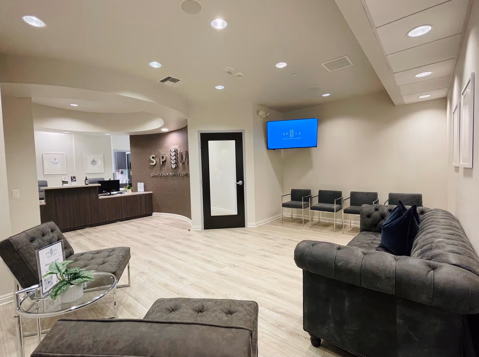 Modern medical reception area with a curved desk, seating, and wall-mounted TV.