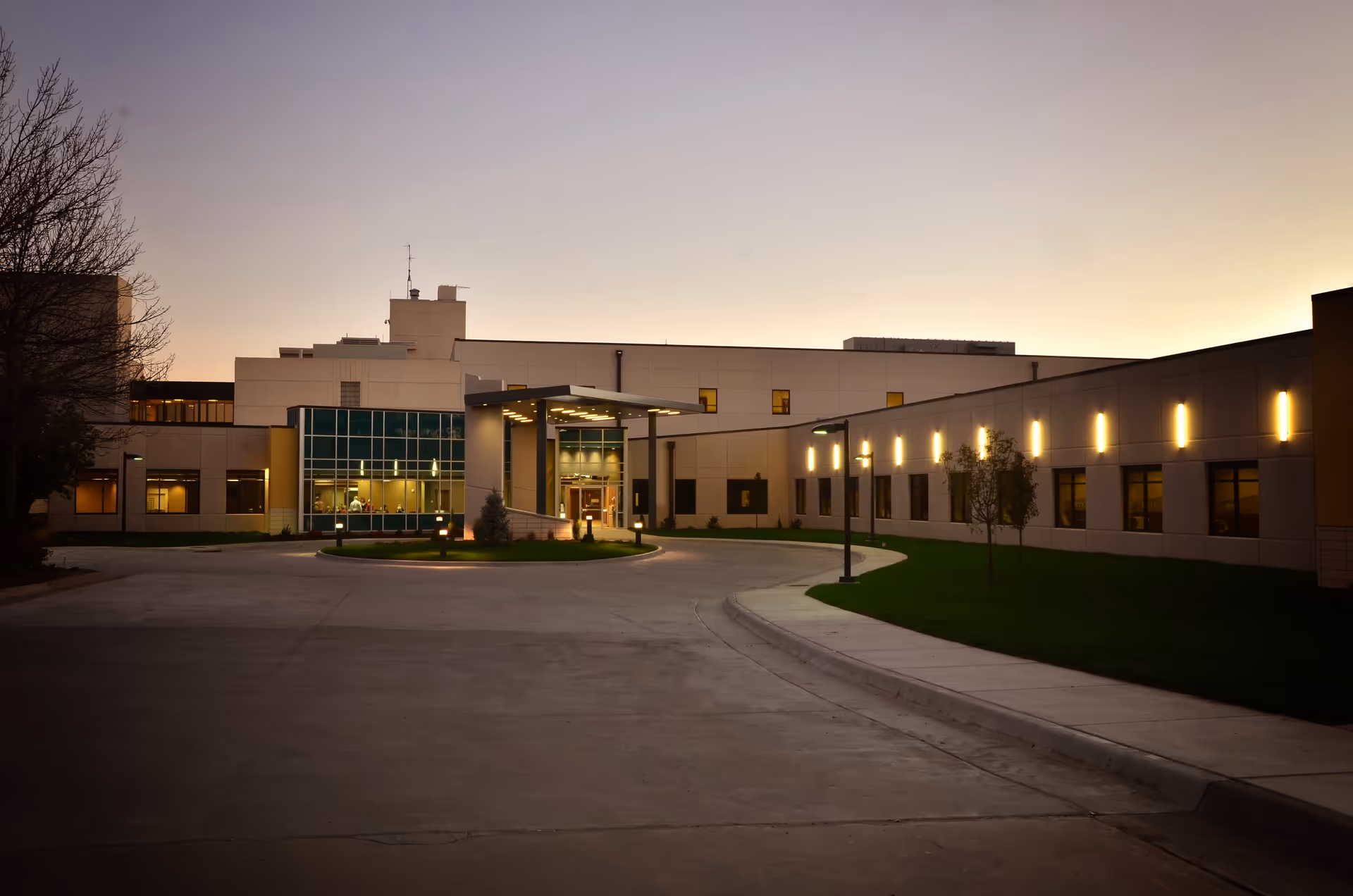 Exterior view of Pratt Regional Medical Center at dusk, with lit entrance and curved driveway.