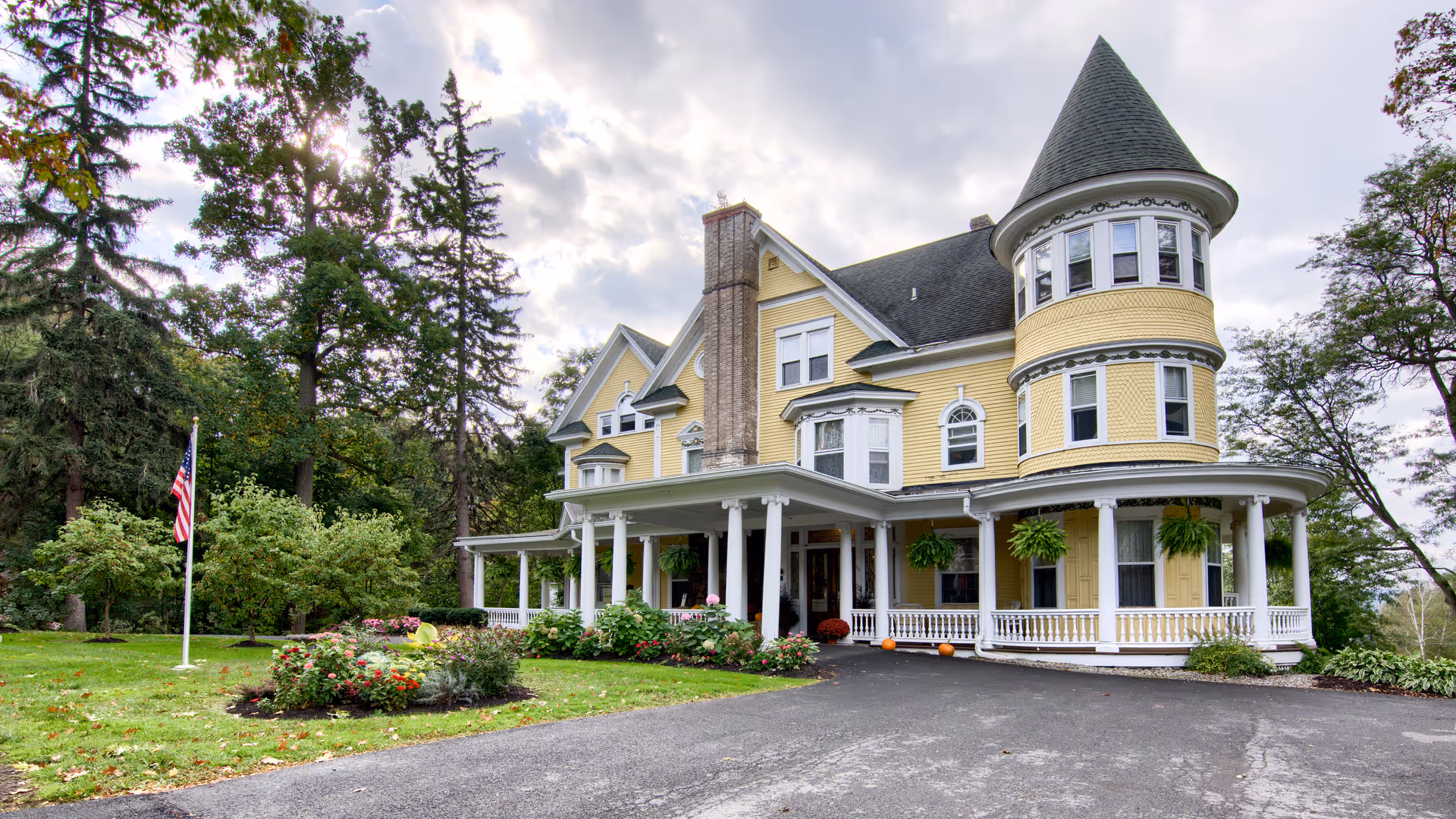 Yellow Victorian-style senior living building with wraparound porch and turret.