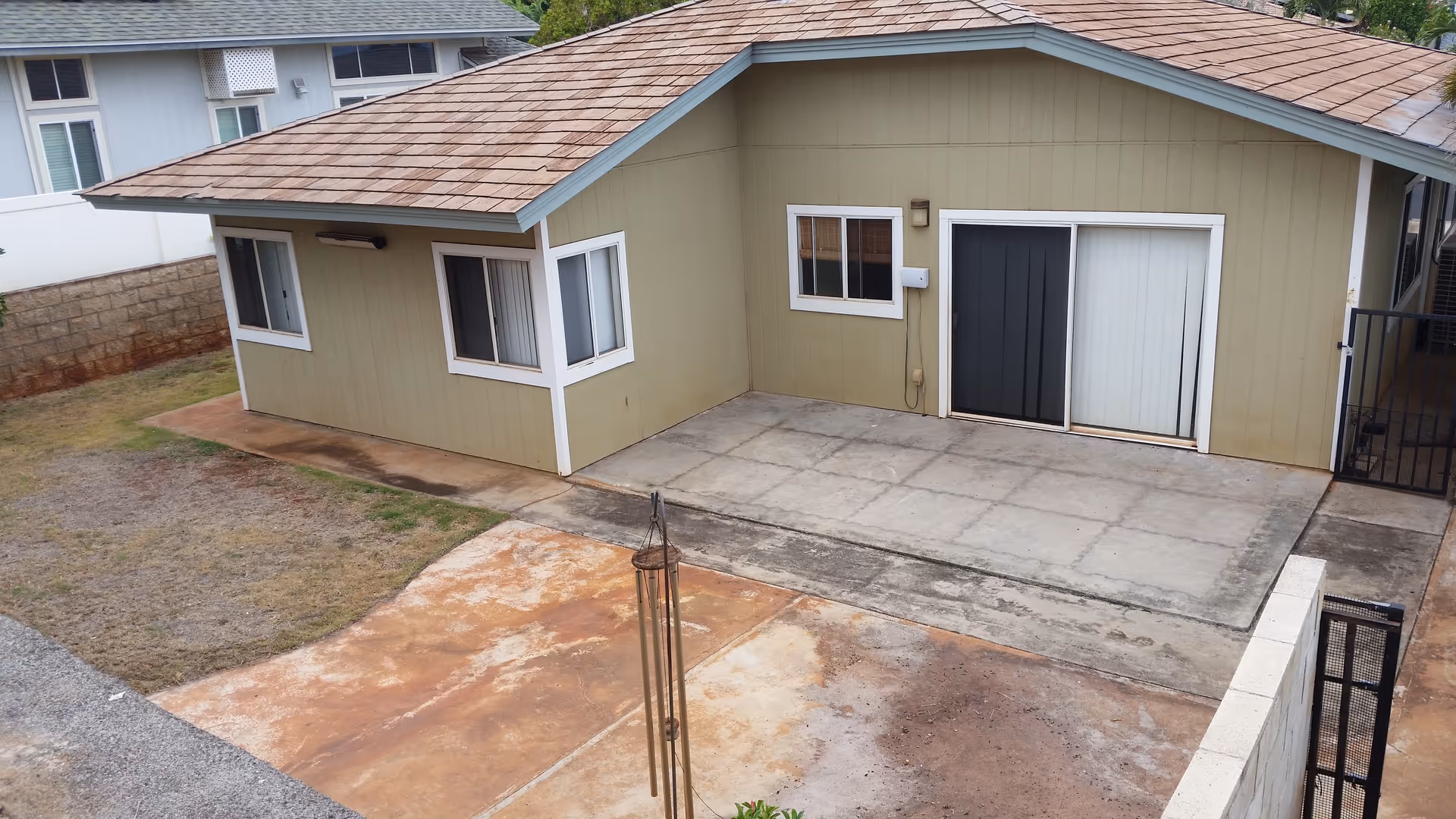 A beige single-story building with a large concrete patio and sliding doors.
