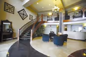 Curved staircase in a spacious, well-lit lobby with seating and second-floor railing.