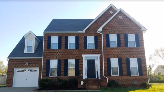 Two-story brick facility with a garage, black shutters, and a white front entry.