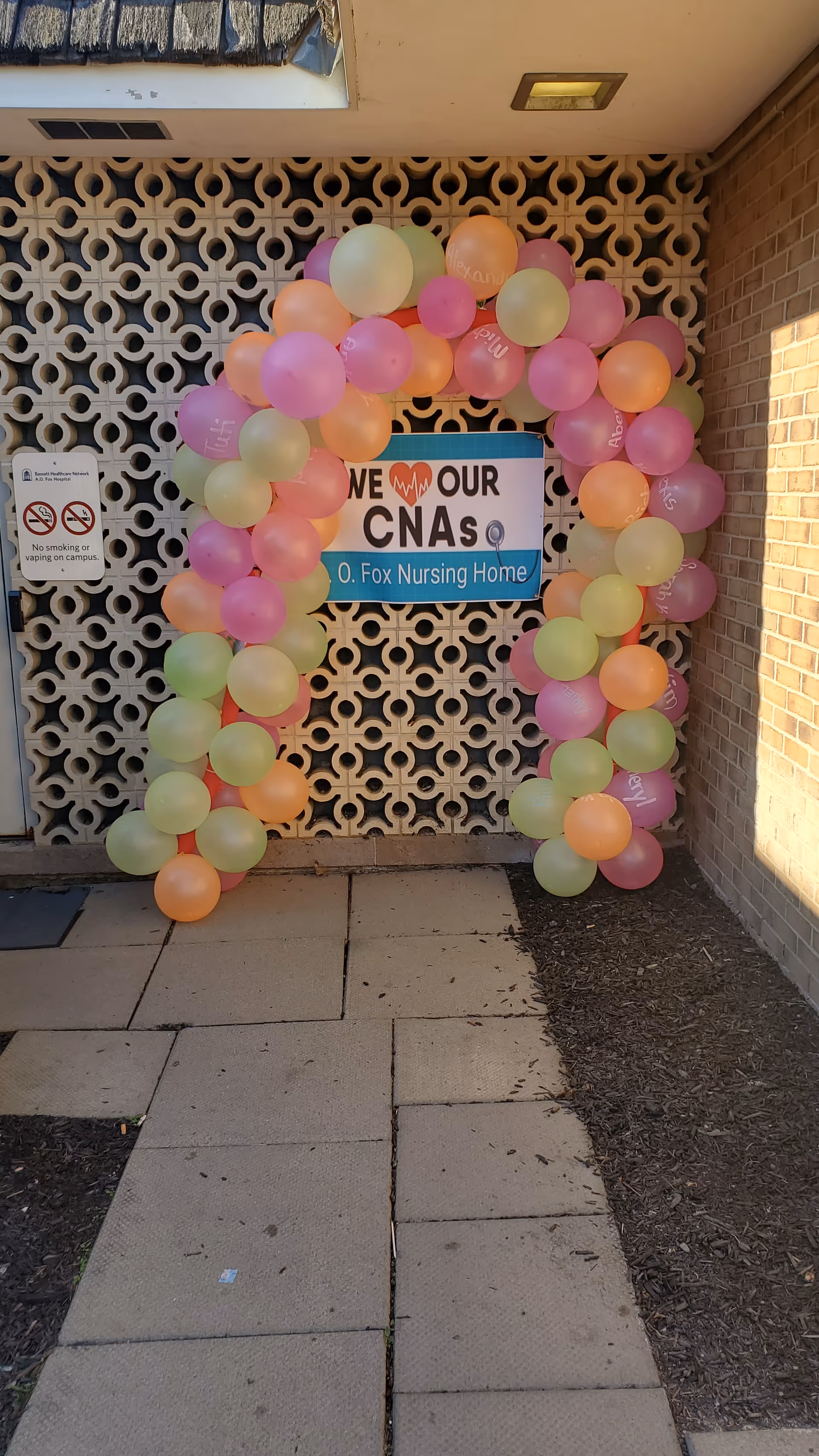 Colorful balloon arch frames the entrance to a nursing home exterior.