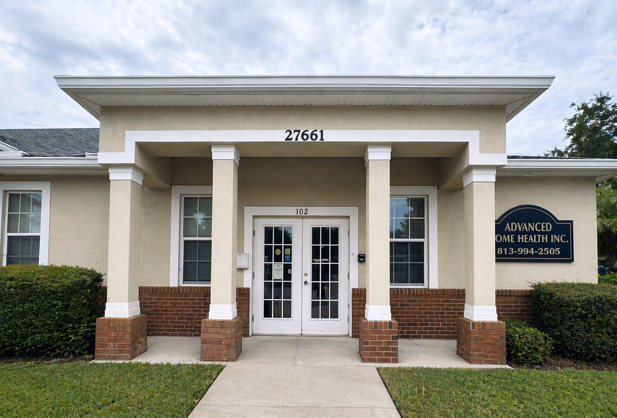 Front entrance of a beige building with white columns and an Advanced Home Health Inc. sign.