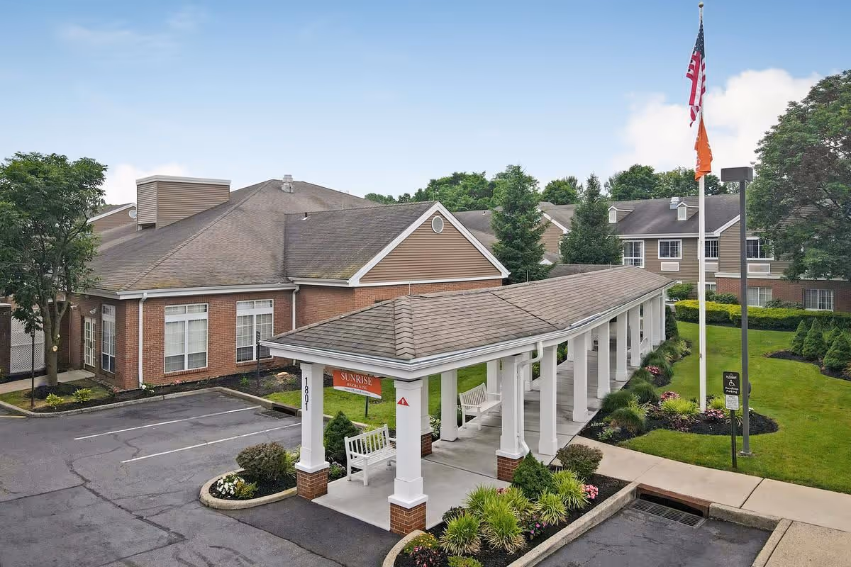 Exterior view of a brick senior living facility with a covered entrance and manicured landscaping.