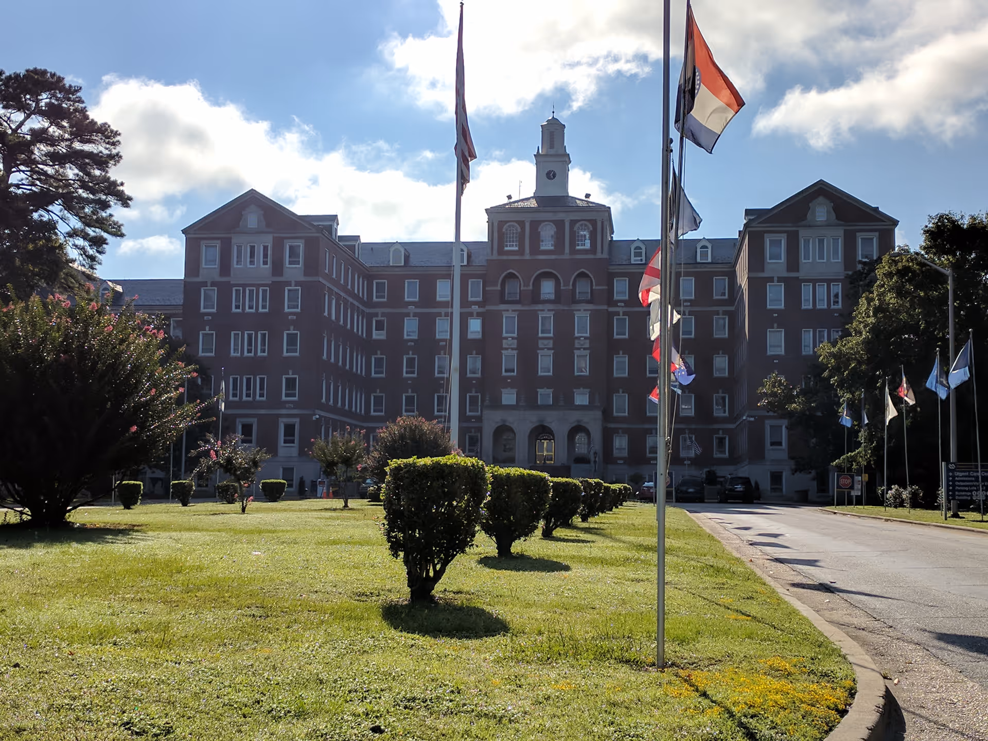 Large brick VA Medical Center building with flagpoles and manicured lawn in front.