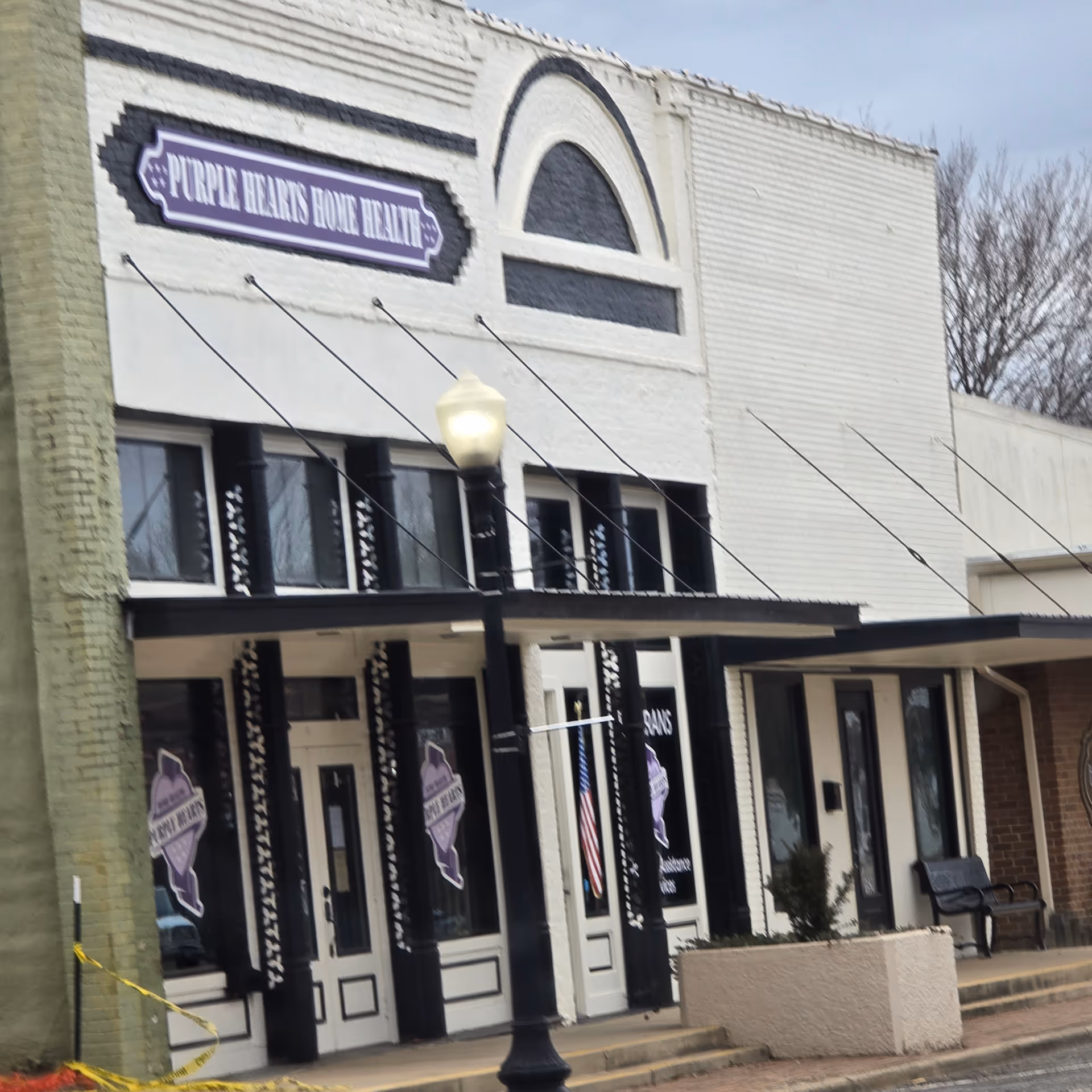 Exterior view of a white building with Purple Hearts Home Health LLC sign.
