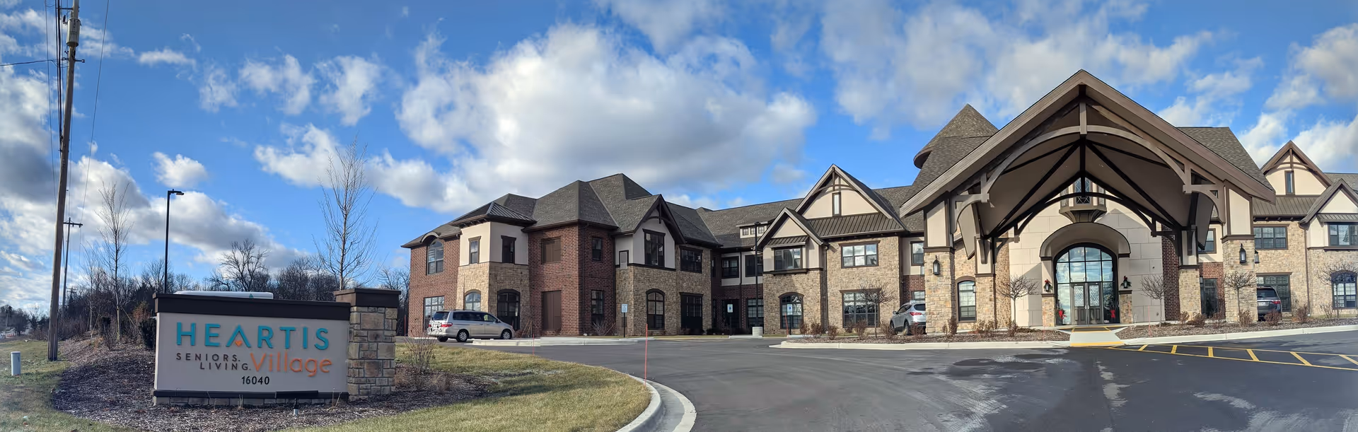 Exterior view of a senior living facility with a grand entrance and parking.