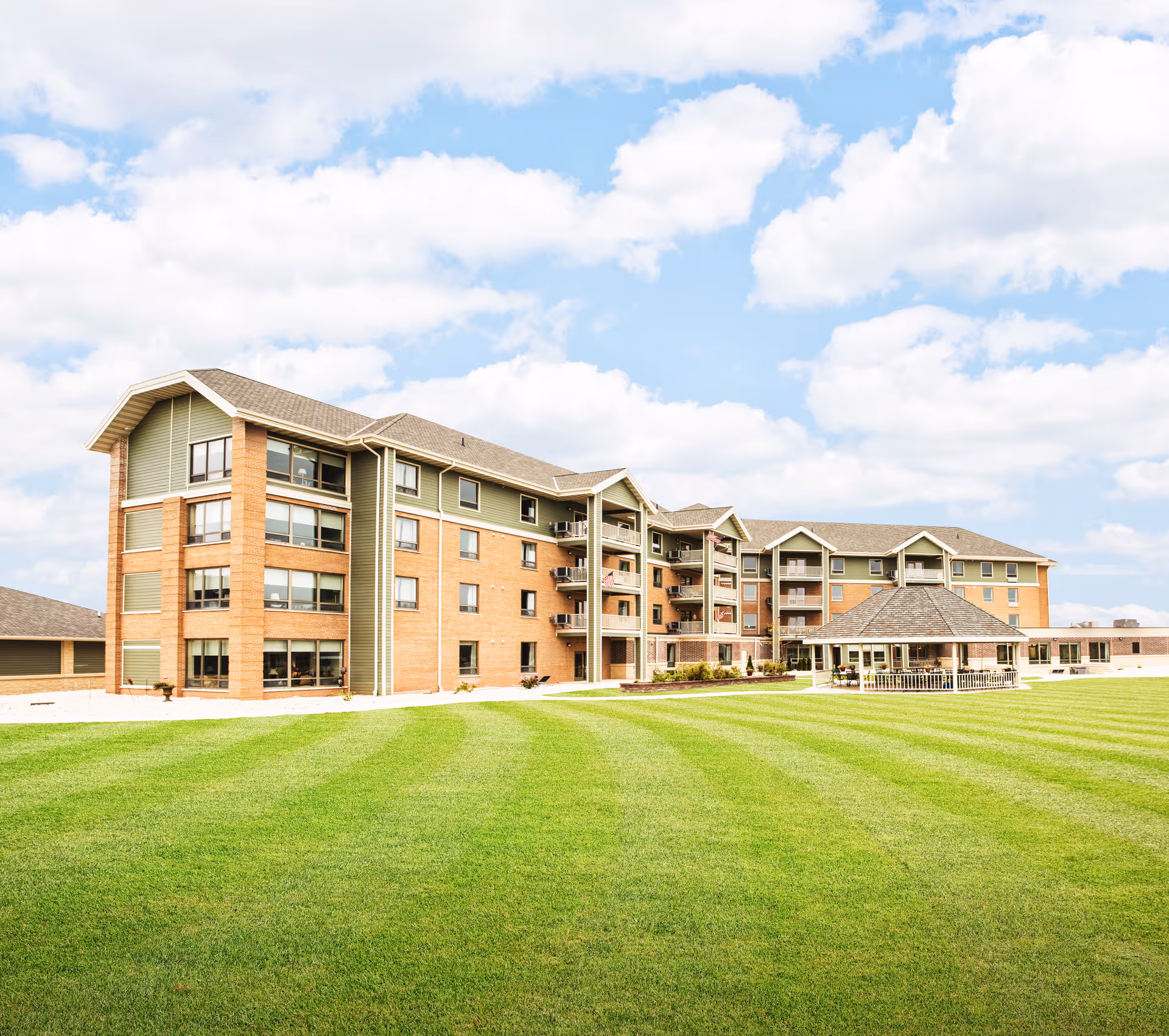 Exterior view of a multi-story senior living building with a green lawn.