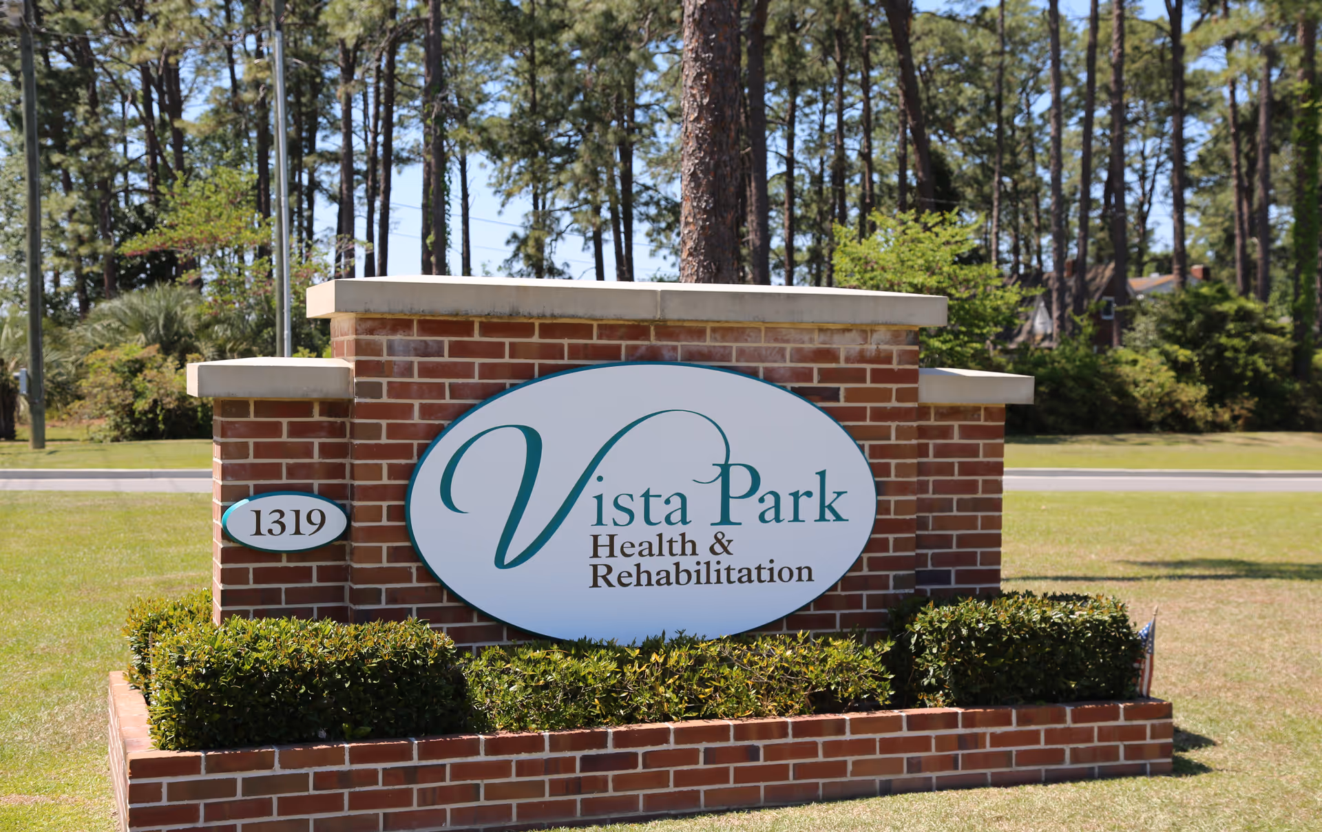 Brick entrance sign for Vista Park Health and Rehabilitation with neatly trimmed shrubs.