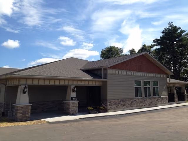 Front view of a single-story senior living building with a covered entry and stone façade.