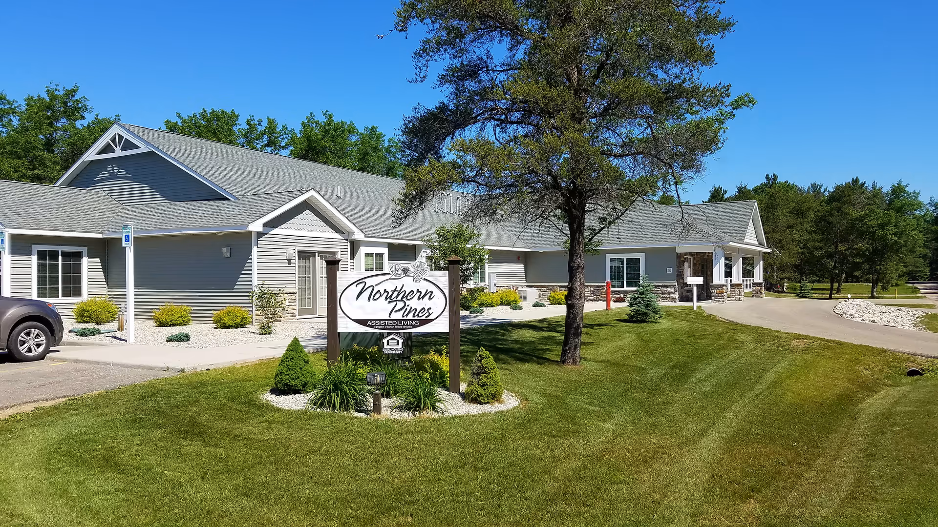 Front exterior of Northern Pines Assisted Living building with a landscaped lawn and entrance sign.