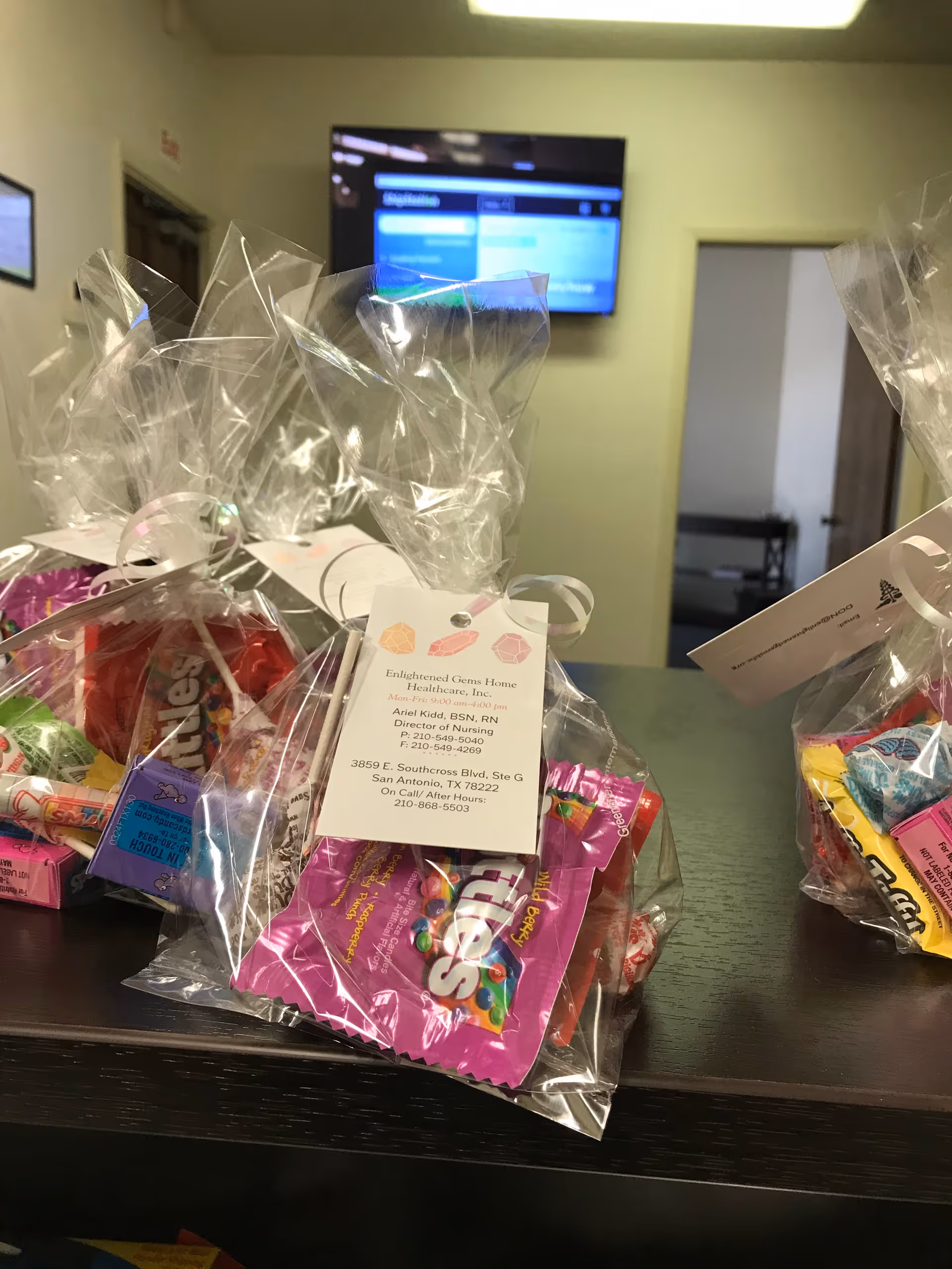 Gift baskets wrapped in cellophane sit on a dark counter inside a senior care facility.