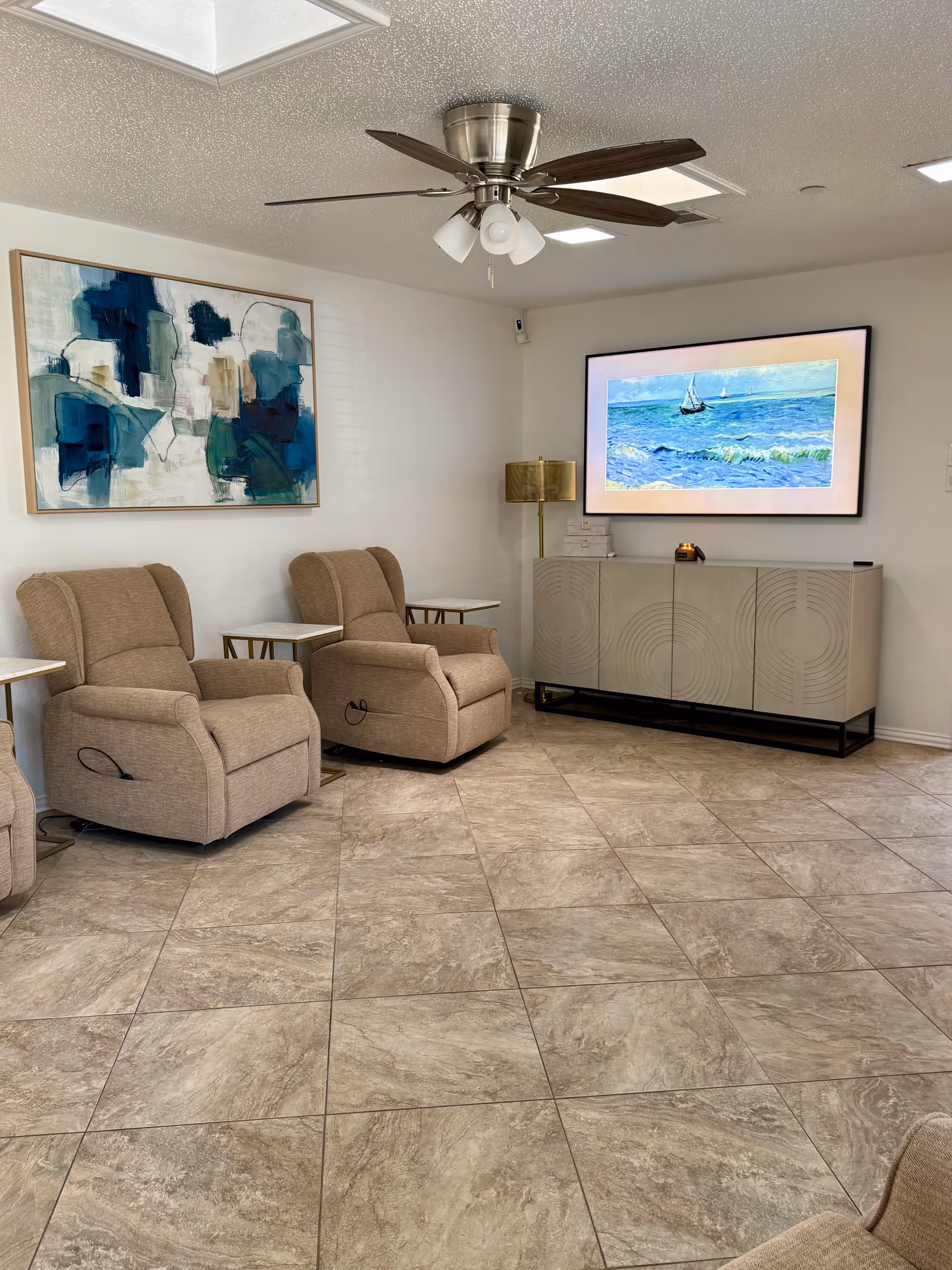 A quiet senior living lounge with beige recliners, a TV, and abstract art.