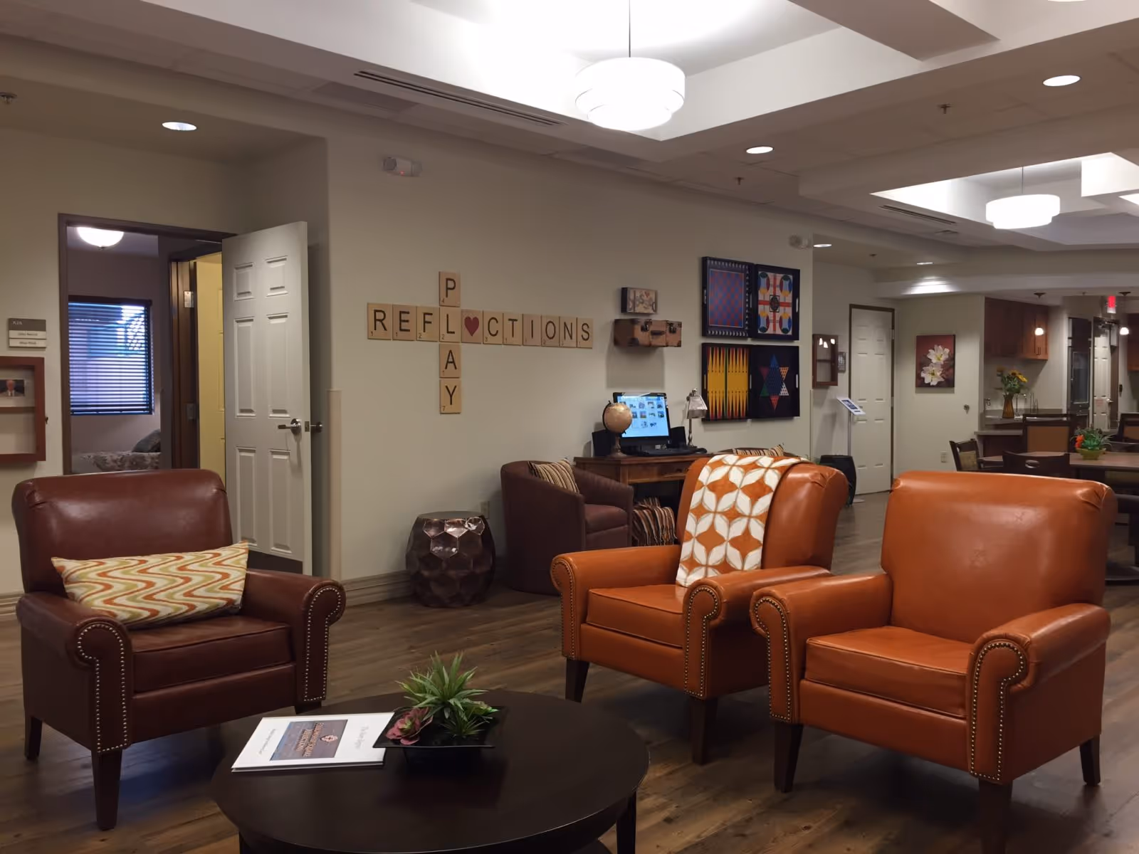 Community seating area with three leather armchairs, a coffee table, and wall decor spelling 'REFLECTIONS'.