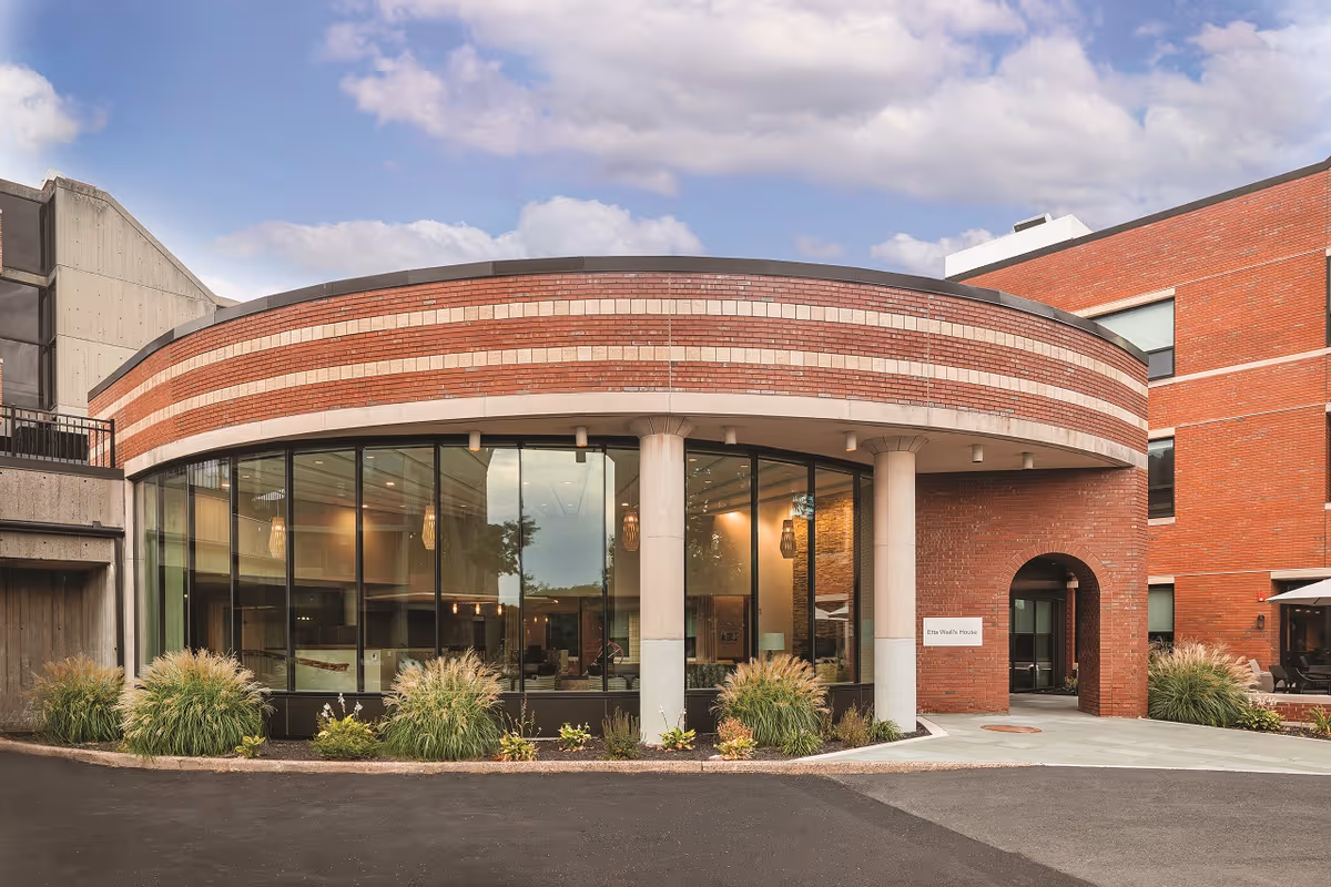 Exterior view of a curved brick building with glass storefront and columns.