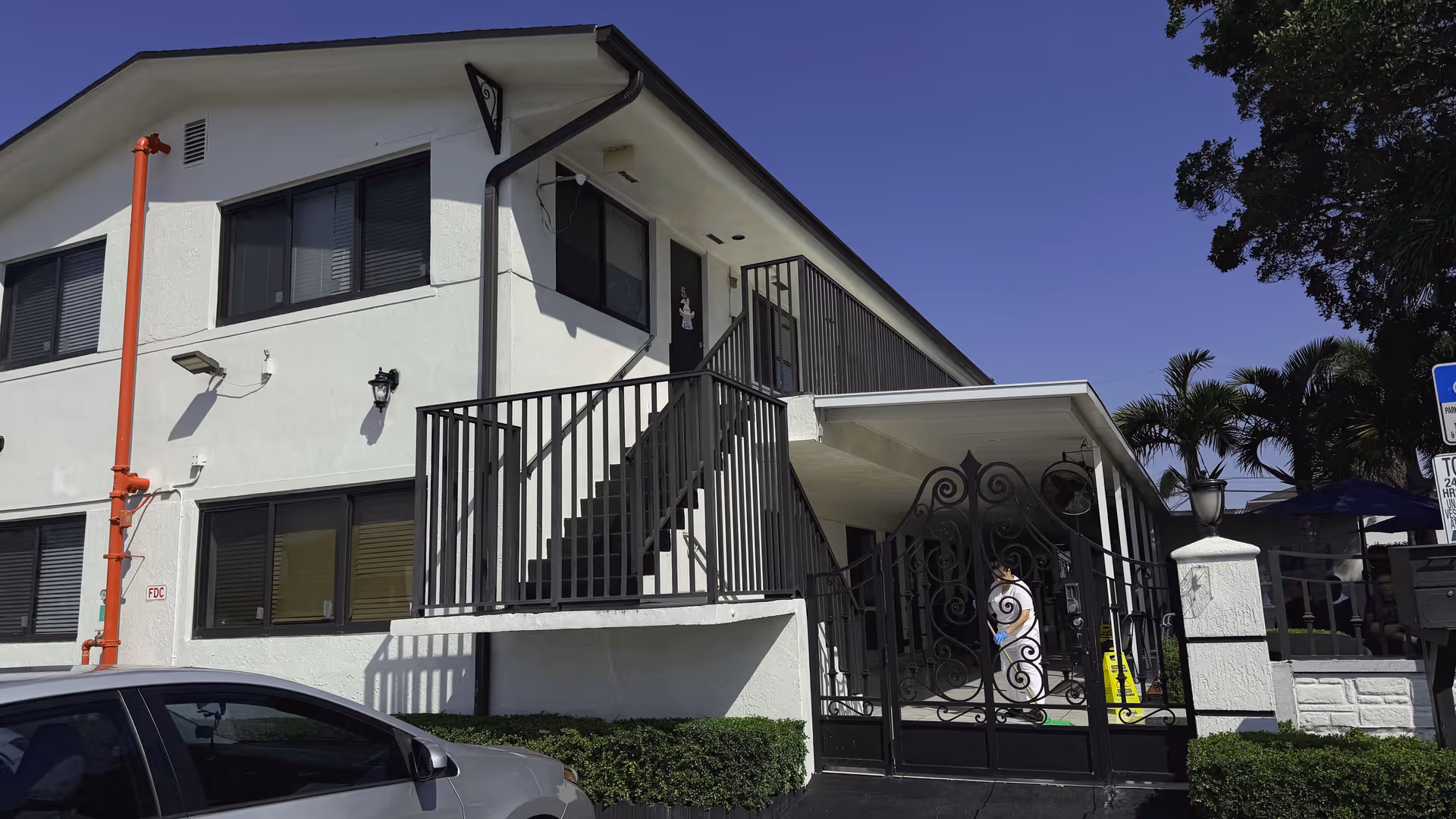 White two-story building with a decorative black gate and stairs to entrance