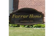 A Farrar Home sign on a brick building with a manicured lawn.