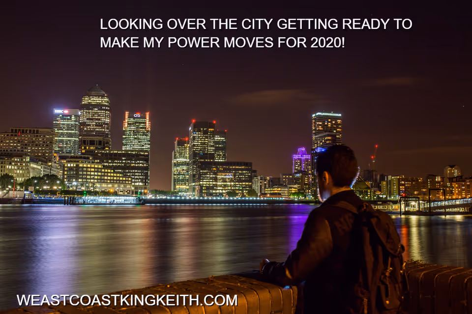 A man stands by a railing, gazing at a brightly lit city skyline across the water.