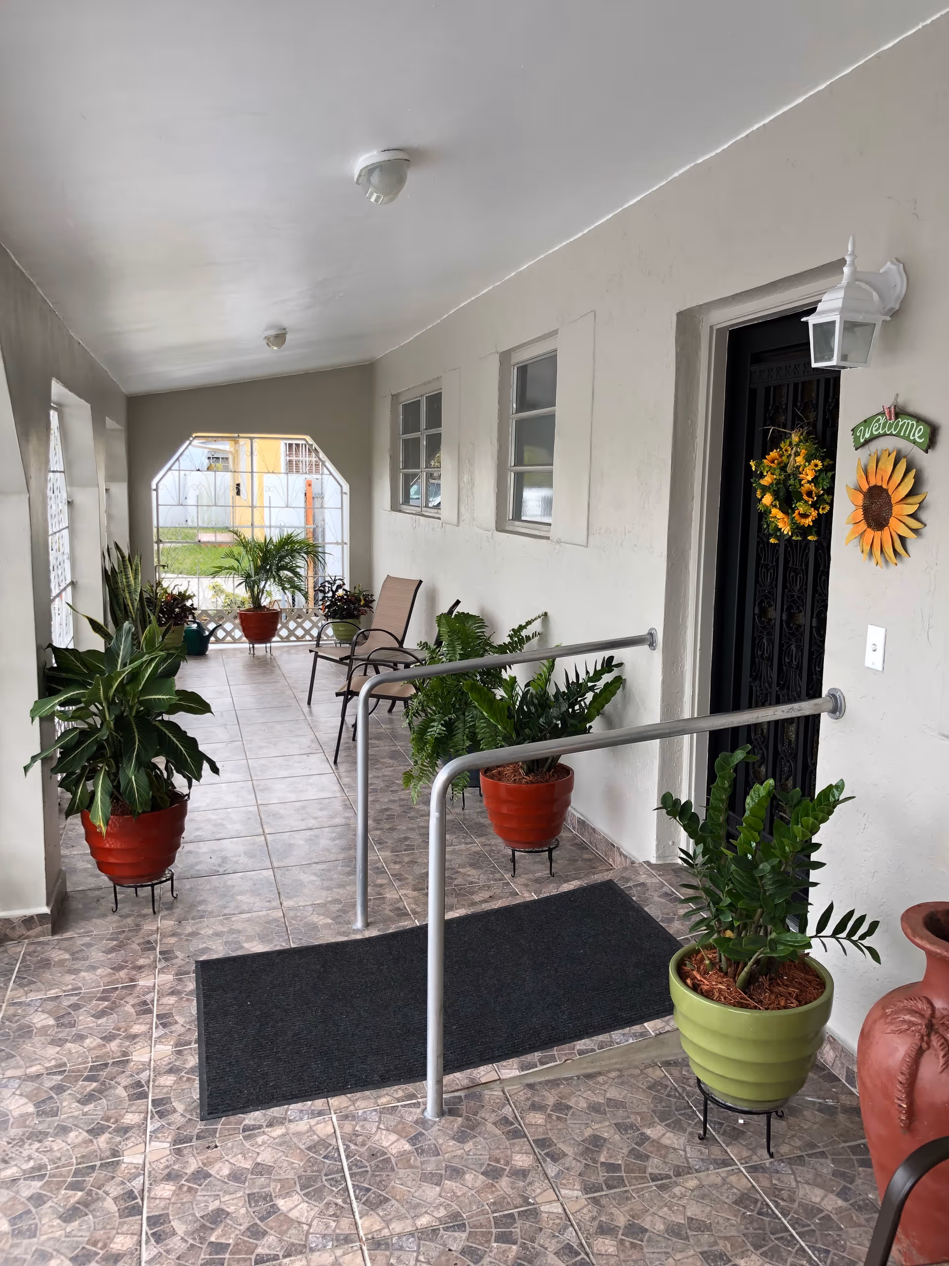 Covered porch at Sunshine Home ALF with potted plants and seating area.
