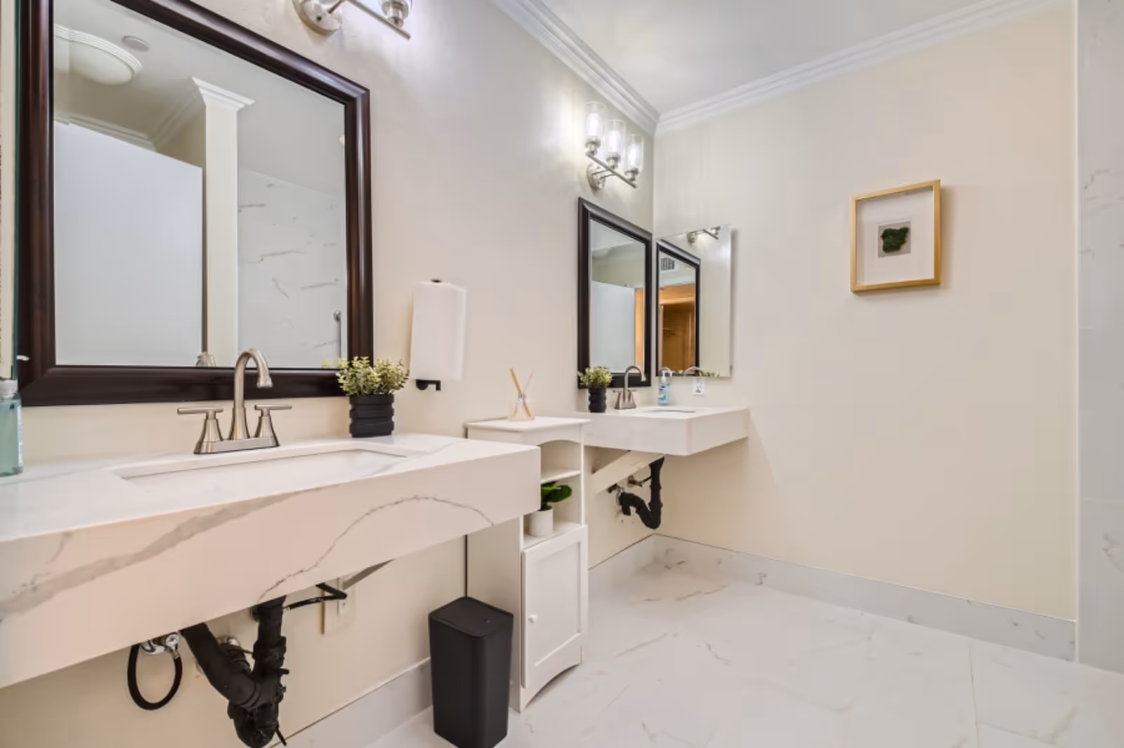 Double-sink marble vanity with framed mirrors in a bright, clean bathroom.