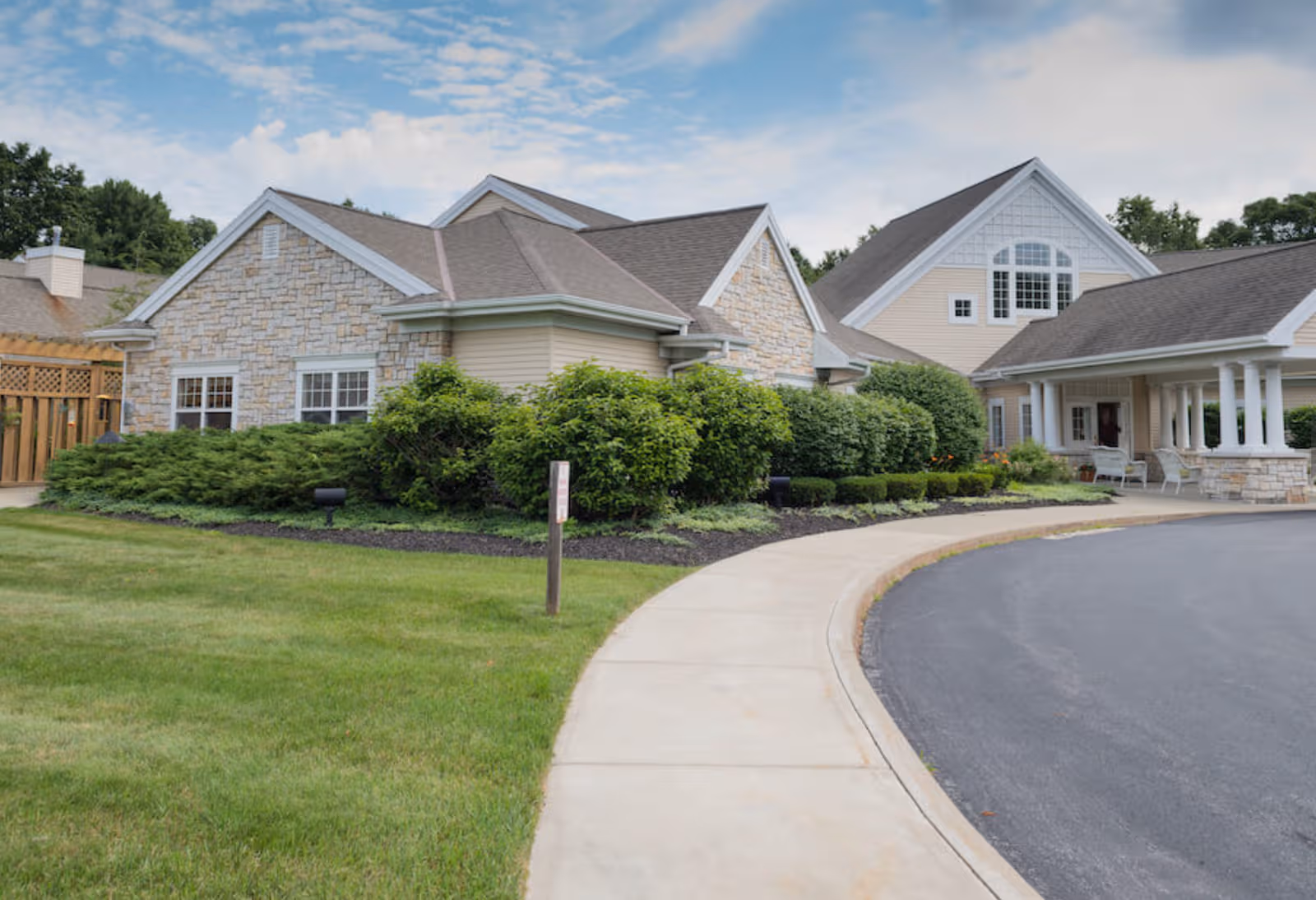 Exterior view of Peregrine Senior Living at Clifton Park, with stone facade and entry porch.