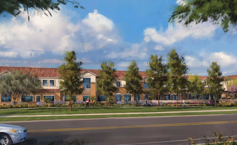 A senior living facility exterior with a red-tiled roof, trees, and a street in front.