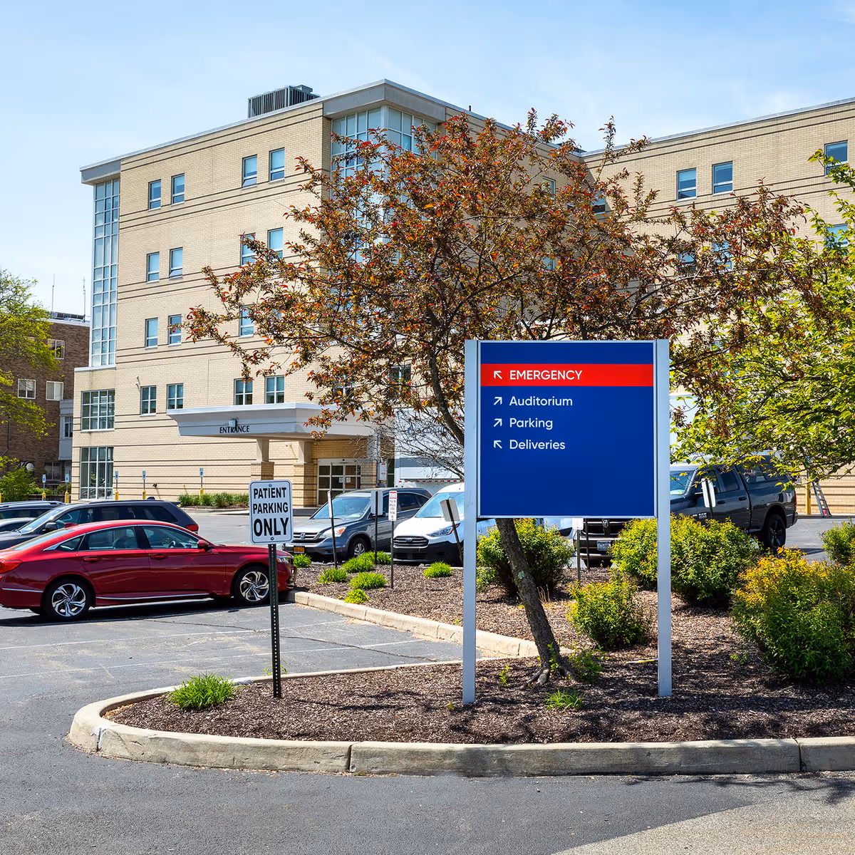 Exterior view of a medical facility with a blue sign and parked cars.