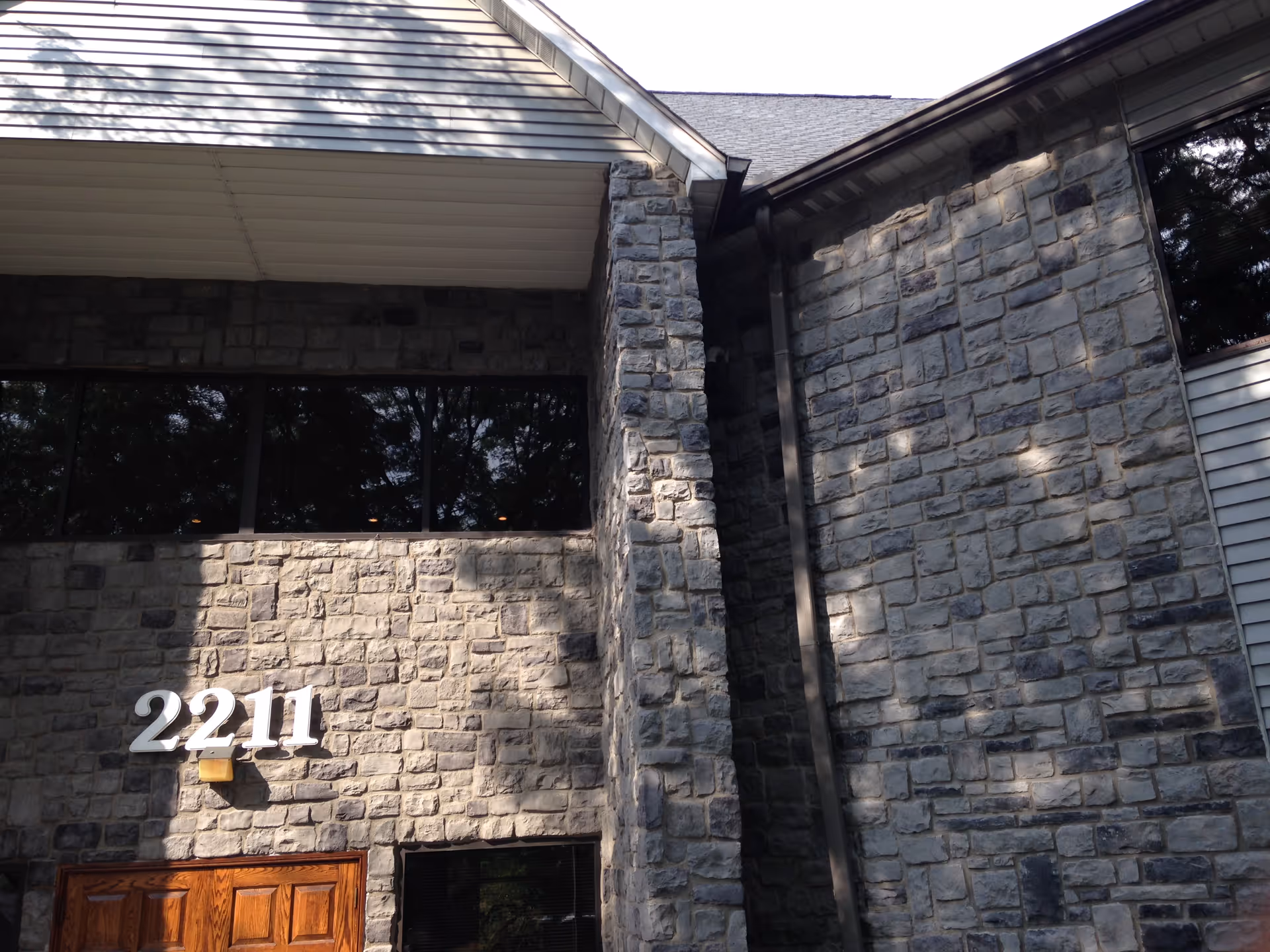 Stone exterior wall with a wooden front door and the number 2211.