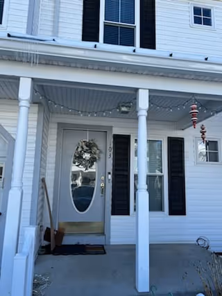 Front porch of a white senior care home with wreath and string lights.