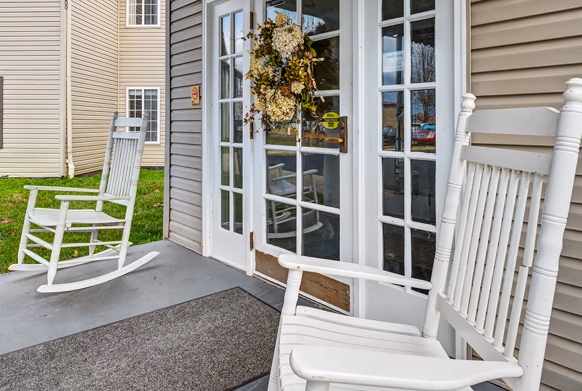 White rocking chairs on a porch outside Bell Oaks Place entrance with a wreath.